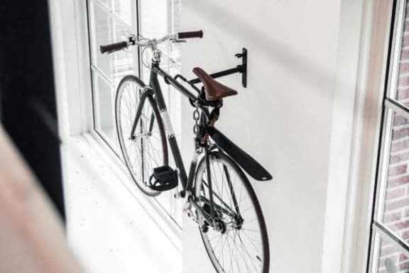 a bike hanging in a window on a wall