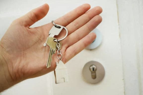 a hand holding a set of keys next to a white door