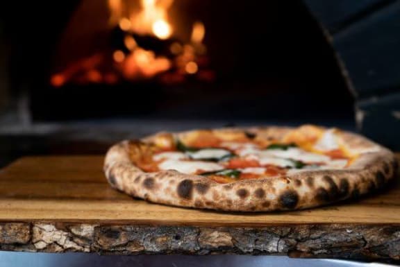 a pizza sitting on top of a wooden cutting board
