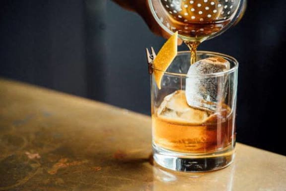 a glass of alcohol being poured into a cocktail
