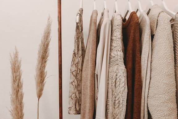 a row of coats hanging on a rack next to some ears of wheat