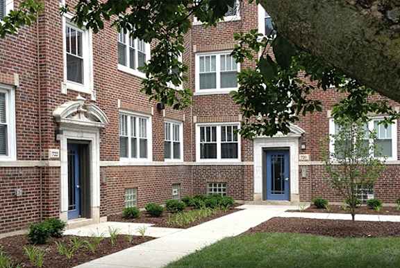 a brick apartment building with blue doors and a sidewalk
