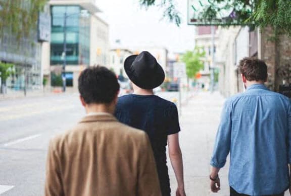 three men walking down the street in the city