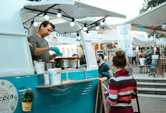 a food truck at a festival with a little girl looking at it