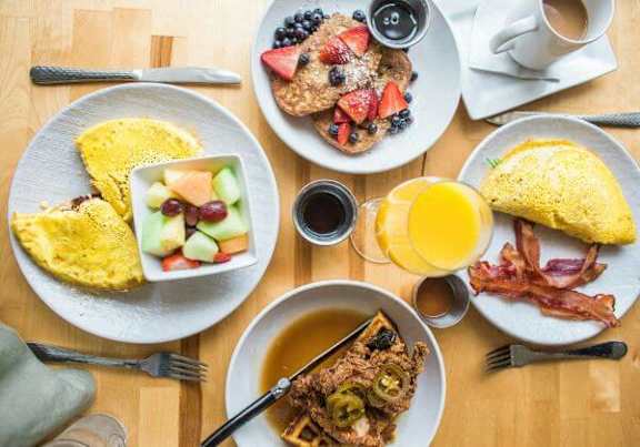 a wooden table topped with plates of breakfast food