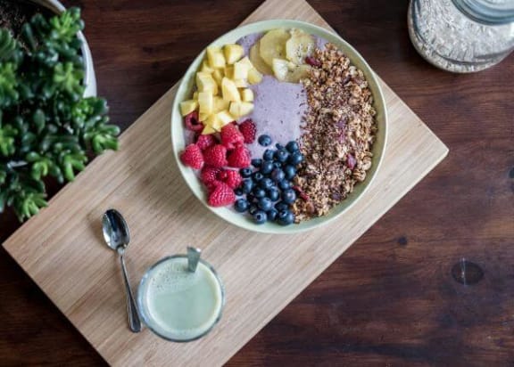a bowl of cereal and fruit on a wooden table