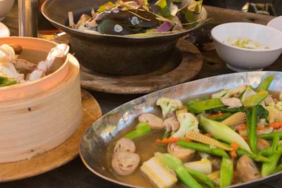 A variety of vegetables are being cooked in a large metal pot.