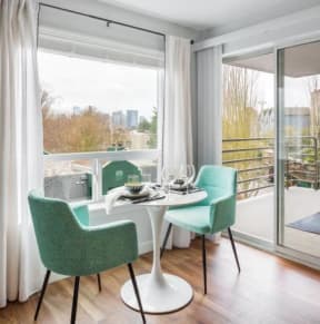 a living room with a table and chairs and a balcony