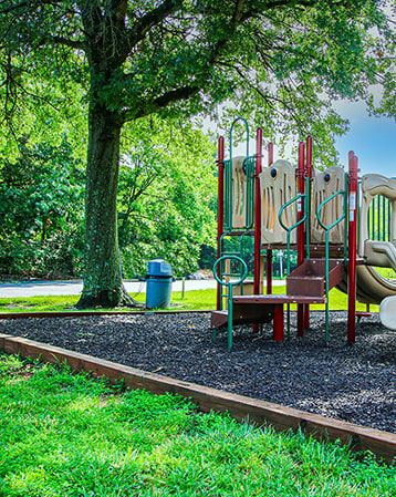 a playground with a swing set and slides in a park