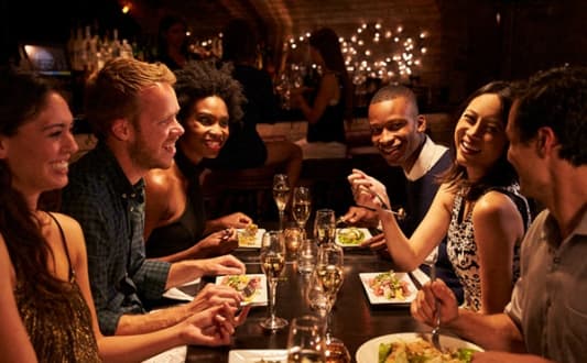 a group of people sitting around a table eating at a restaurant