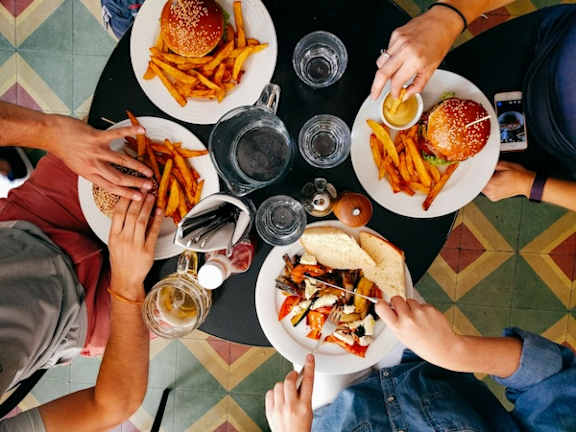 A top view of a group of people sharing a meal with burgers and fries.