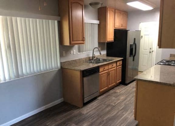 A kitchen with wooden cabinets and a black refrigerator.