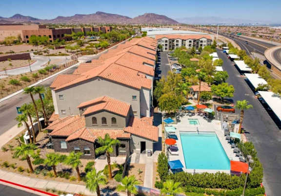 A swimming pool is located in front of a building with a red tiled roof.