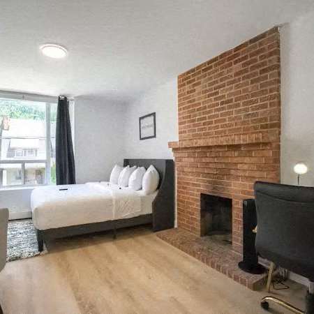 A bedroom with a brick fireplace and a bed with white pillows.