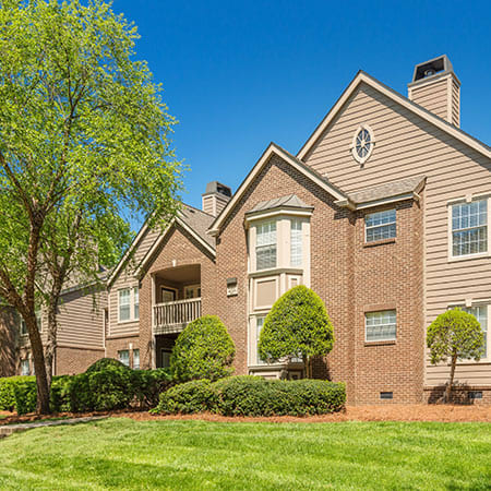 a brick apartment building with trees and grass at Radbourne Lake Apartments, Charlotte, 28269