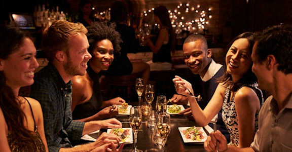a group of people sitting around a table eating at a restaurant