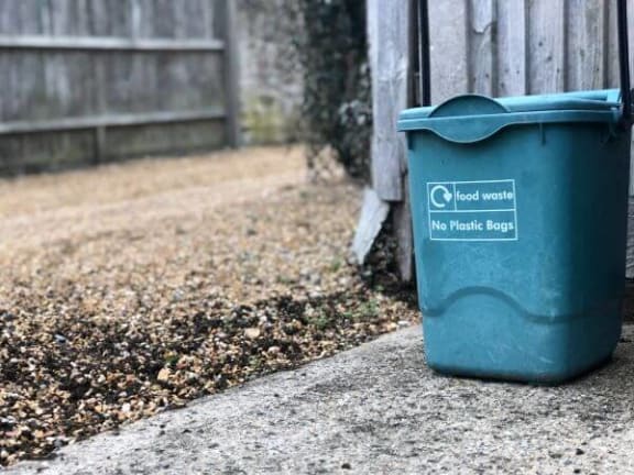 a blue recycling bin sitting next to a fence