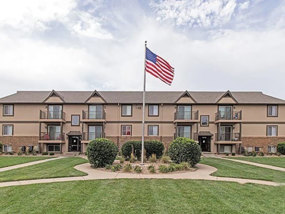 a flagpole with an american flag in front of an apartment complex