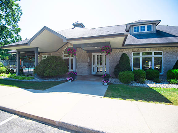 the front of a brick house with flowers on the driveway