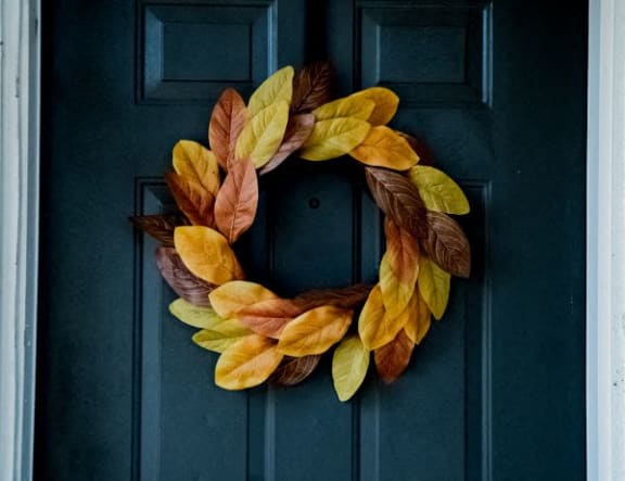 a wreath of autumn leaves on a blue door