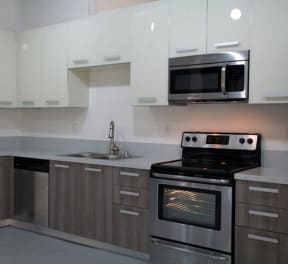 a kitchen with stainless steel appliances and white cabinets at Binford Lofts Apartments, Los Angeles , California