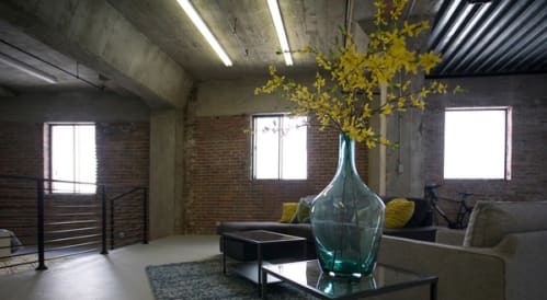 a living room with a glass vase with flowers on a table at Binford Lofts Apartments, Los Angeles