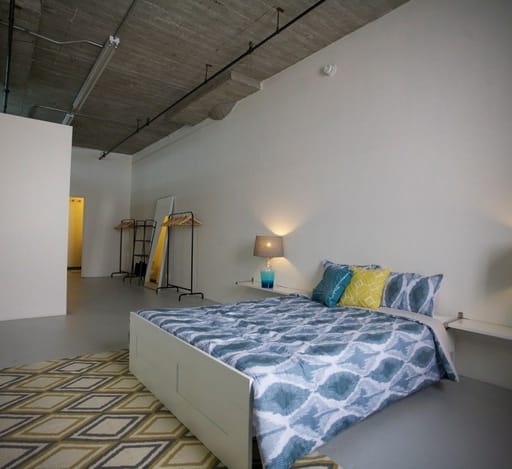 a bedroom in a loft with a bed and a geometric rug at Binford Lofts Apartments, Los Angeles , California