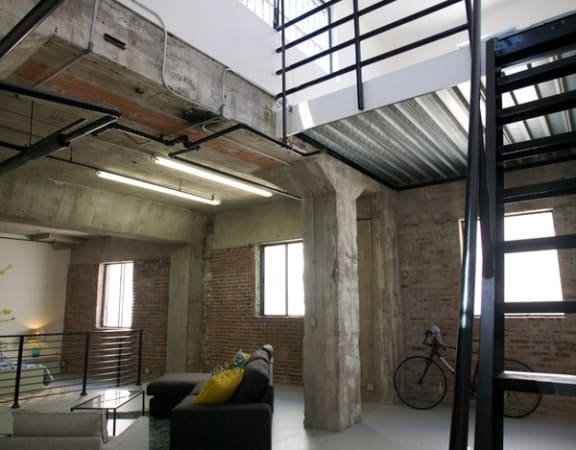 a loft with a staircase and a couch and a bike in it at Binford Lofts Apartments, Los Angeles , 90013