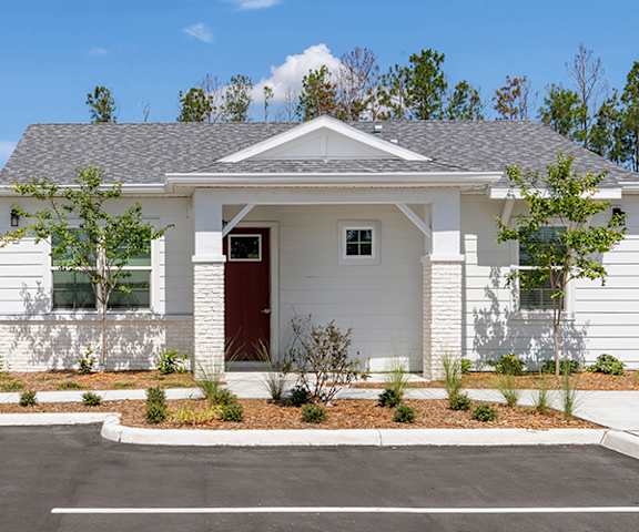 A white house with a red door and a grey roof.