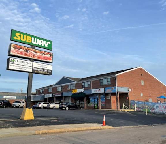 A Subway restaurant sign is displayed in front of a brick building.