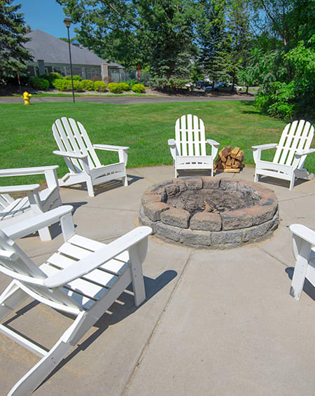 a group of white rocking chairs around a fire pit