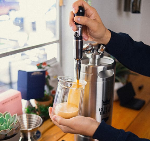 a person pouring orange juice from a juicer into a glass