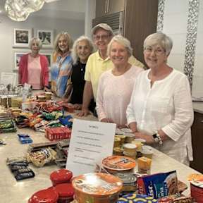 A group of people standing behind a table full of food items.