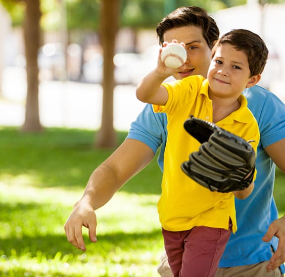 a boy in a yellow shirt throwing a baseball to a man in a blue shirt