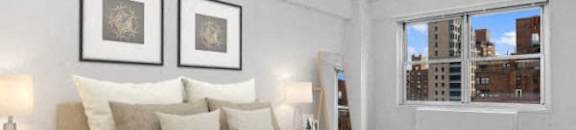 A bedroom with a large bed and a window overlooking a cityscape at The Caldwell Apartments, New York, 10028