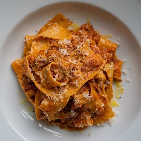 A plate of pasta with a tomato-based sauce and grated cheese on top.