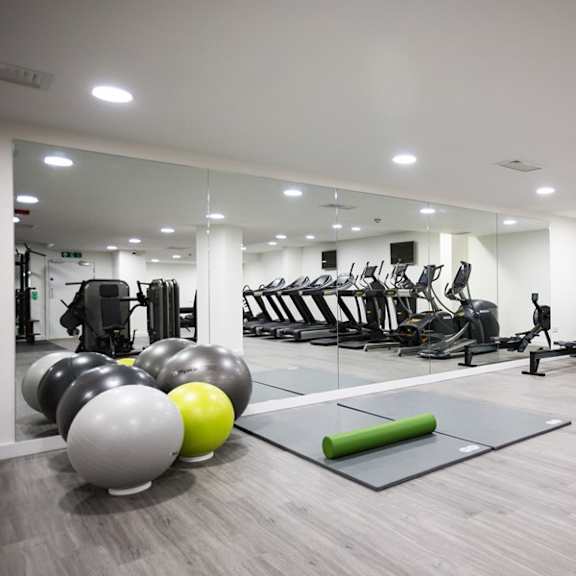 a gym with fitness equipment and exercise balls on the floor