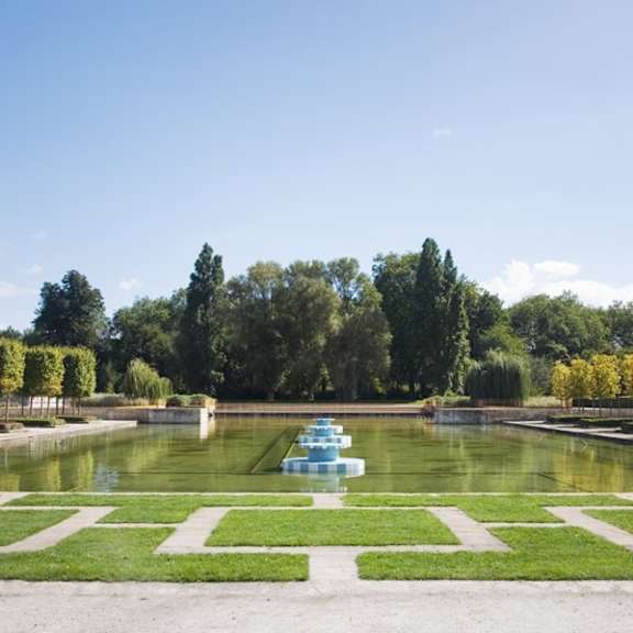 a large fountain in the middle of a pond in a park