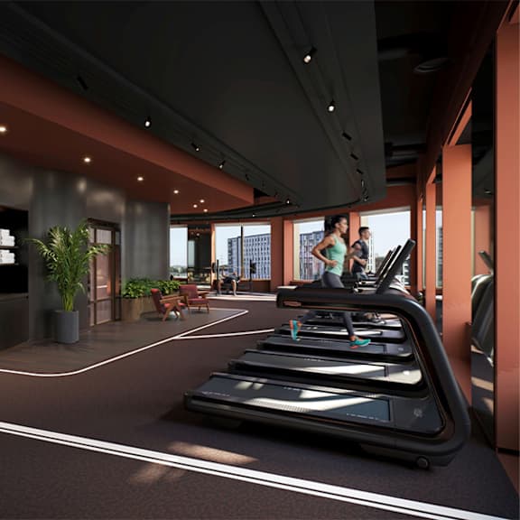 A woman is running on a treadmill in a gym with a city view.