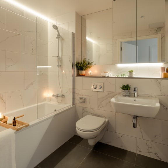A modern bathroom with a white toilet, a bathtub with a shower head, a sink, and a mirror.