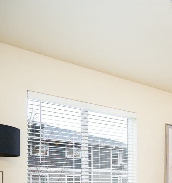 A living room with a beige couch, a coffee table, and a ceiling fan. at Fairview Village Apartments, Fairview, OR, 97024