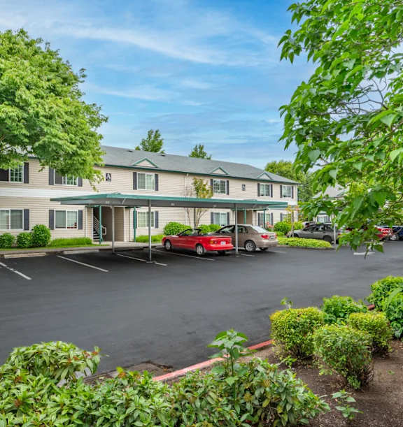 A parking lot in front of a building with a red car parked in the front.at Vancouver Mall Apartments, Washington
