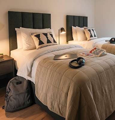 A bedroom with a bed, a backpack, and a lamp.