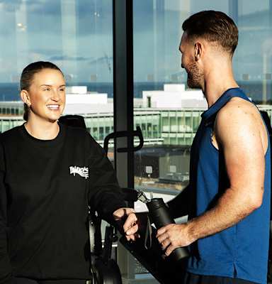 A man and a woman are shaking hands in a gym.