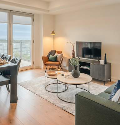 A living room with a grey sofa, a black dining table, and a television at Cherrywood Apartments, D18 VY3V, DUBLIN 18
