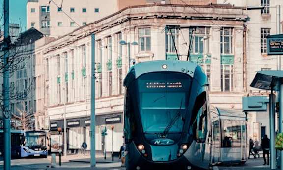 A blue train is on the tracks in the city.