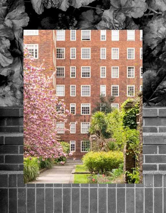 A brick building with windows and a garden in front.