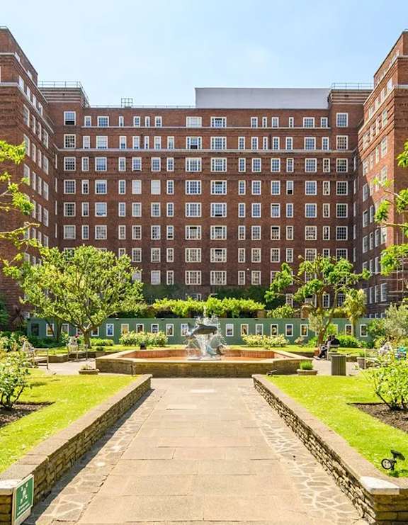 A large brick building with a fountain in front.