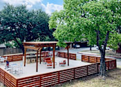 Thumbnail 6 of 27 - Outdoor patio deck with pergola and horizontal slat fencing at The Colony Apartments, Universal City, TX