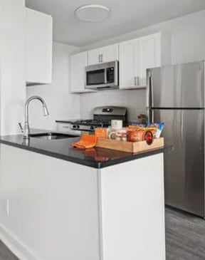 A kitchen with a black counter top and white cabinets.